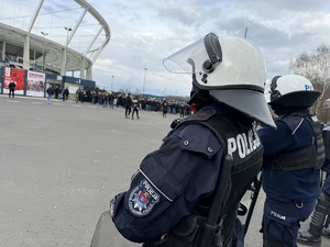 Na pierwszym planie umundurowani policjanci na tle Stadionu Śląskiego i zebranych kibiców
