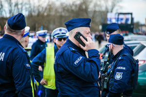 Umundurowani policjanci. Na pierwszym planie policjant rozmawiający przez telefon
