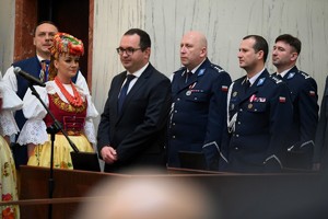 kolorowe zdjęcie zrobione w sali obok siebie stoją zaproszeni goście oraz komendant wojewódzki