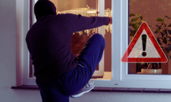 Grafika przedstawiająca włamywacza w kominiarce wchodzącego przez okno i znak uwaga.