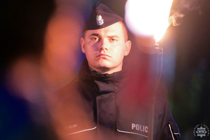 Na zdjęciu policjant z pochodnią w ręku.
