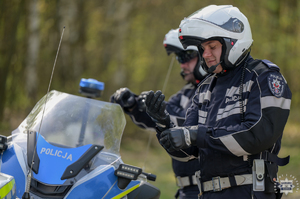 Na zdjęciu dwaj policyjni motocykliści w kasku siedzący na motocyklach.