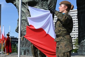 Zdjęcie przedstawia żołnierza trzymającego flagę państwową