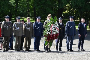 Zdjęcie przedstawia delegację służb mundurowych z kwiatami