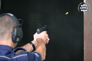 Na zdjęciu widać policjanta oddającego strzał z broni.