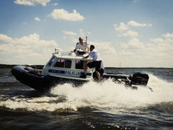 Na zdjęciu umundurowani policjanci na łodzi motorowej.