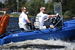 Na zdjęciu widać dwóch umundurowanych policjantów, patrolujących zbiornik wodny łodzią motorową.