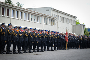 Zdjęcie przedstawia stojących na baczność w szeregu strażaków w umundurowaniach galowych