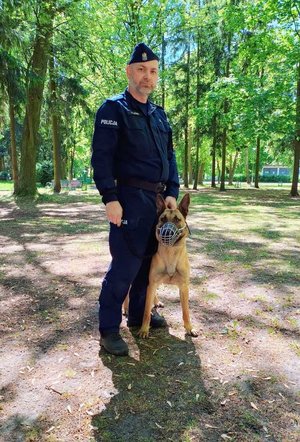 Zdjęcie policjanta oraz policyjnego psa rasy owczarek.