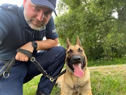 Zdjęcie policjanta oraz psa owczarka.