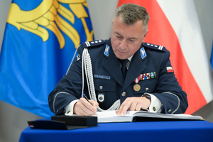 Zastępca Komendanta Głównego Policji podpisuje pamiątkową księgę