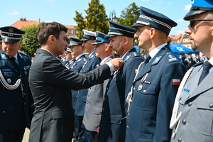 Wojewoda Śląski przypina medal policjantowi