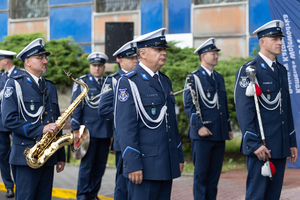 Policjanci z orkiestry ze swoimi instrumentami stoją przed budynkiem komendy