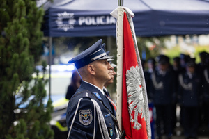 Policjant stoi przy poczcie sztandarowym