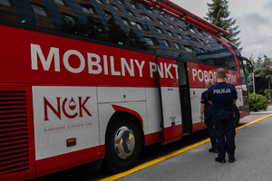 Zdjęcie kolorowe. Na zdjęciu widać autobus z krwiodawstwa oraz stojących policjantów przed nim