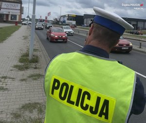 Zdjęcie kolorowe. Policjant z urządzaniem do pomiaru prędkości