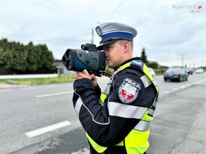 Zdjęcie kolorowe. Policjant z urządzaniem do pomiaru prędkości