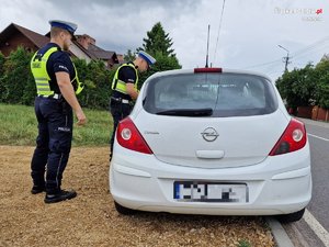 Zdjęcie kolorowe. Policjanci Stoją obok pojazdu