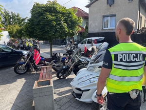 Na pierwszym planie policjant, w tle uczestnicy warsztatów