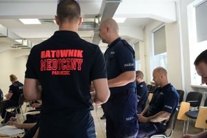 Ratownik medyczny i policjant rozdający arkusze egzaminacyjne