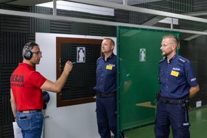 Na zdjęciu instruktor strzelań mówi do policjantów.