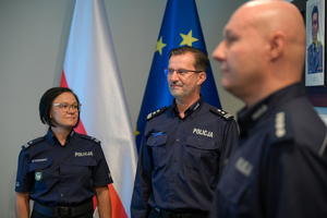 Zbliżenia na umundurowanego policjanta, w tle policjantka w mundurze