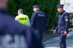 Na zdjęciu widoczni dwaj umundurowani policjanci i jeden zw kamizelce odblaskowej z napisem Policja