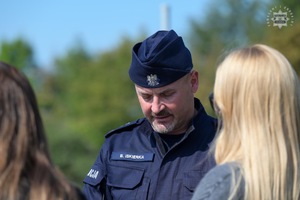 Na zdjęciu widoczny umundurowany policjant rozmawiający z kobietami