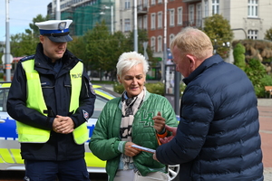 zdjęcie kolorowe przedstawia policjanta wraz z uczestnikami akcji