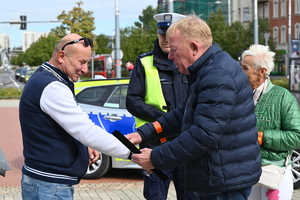 zdjęcie kolorowe przedstawia policjanta wraz z uczestnikami akcji