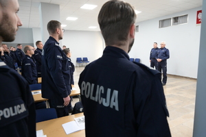 Zdjęcie przedstawiające umundurowanych funkcjonariuszy Policji stojących tyłem do fotografującego.