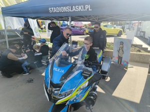 Na zdjęciu widać dziecko siedzące na policyjnym motocyklu