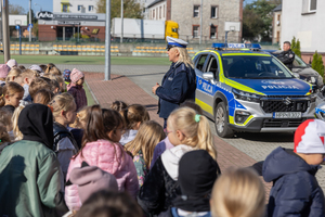 Na zdjęciu policjantka przy radiowozie przemawia do dzieci.