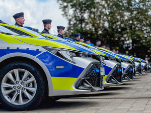 Na zdjęciu umundurowani policjanci stojący przy radiowozach policyjnych