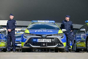 Na zdjęciu umundurowani policjanci stojący przy radiowozach policyjnych