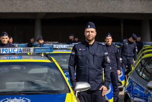 Na zdjęciu umundurowani policjanci stojący przy radiowozach policyjnych