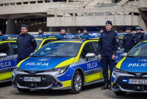 Na zdjęciu umundurowani policjanci stojący przy radiowozach policyjnych