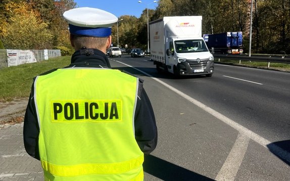 Na zdjęciu umundurowany policjant ruchu drogowego kontrolujący ruch drogowy