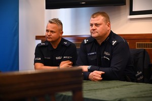 Na zdjęciu jest widocznych dwóch siedzących policjantów