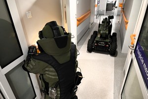 Na zdjęciu widoczny jest policjant w pełnym stroju pirotechnicznym oraz robot pirotechniczny