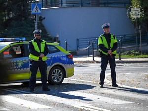 Na zdjęciu dwóch policjantów obok radiowozu.