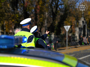 Na zdjęciu policjanci ruchu drogowego wskazujący drogę przechodniowi.