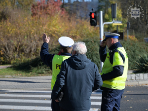 Na zdjęciu dwójka policjantów tłumaczących drogę mężczyźnie.