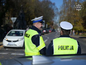 Na zdjęciu dwójka policjantów nadzorujących skrzyżowanie w pobliżu cmentarza.