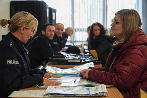 na zdjęciu siedzące przy stole osoby i policjanci