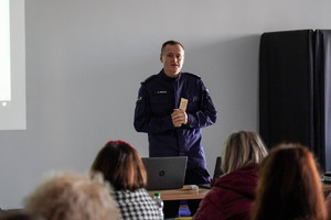 na zdjęciu policjant w trakcie wypowiedzi stojący przed zgromadzonymi osobami