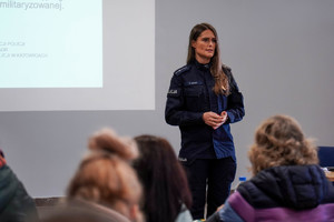 na zdjęciu policjantka w trakcie wypowiedzi stojąca przed zgromadzonymi osobami