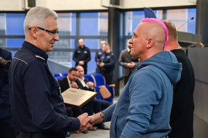 na zdjęciu komendant wojewódzki podający dłoń jednemu z dwóch stojących obok niego mężczyzn.