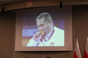 na zdjęciu wyświetlony slajd na którym znajduje się zdjęcie mężczyzny całującego złoty medal.