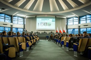 na zdjęciu sala konferencyjna, w niej siedzący na krzesłach mundurowi, pośrodku wyświetlony slajd Konferencja.